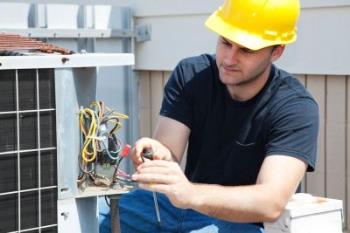 A Furnace World technician repairing an AC in Monument